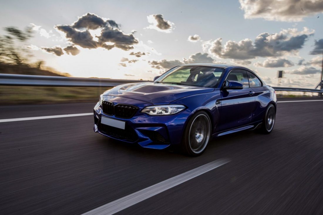 blue-sedan-car-driving-road-cloudy-weather