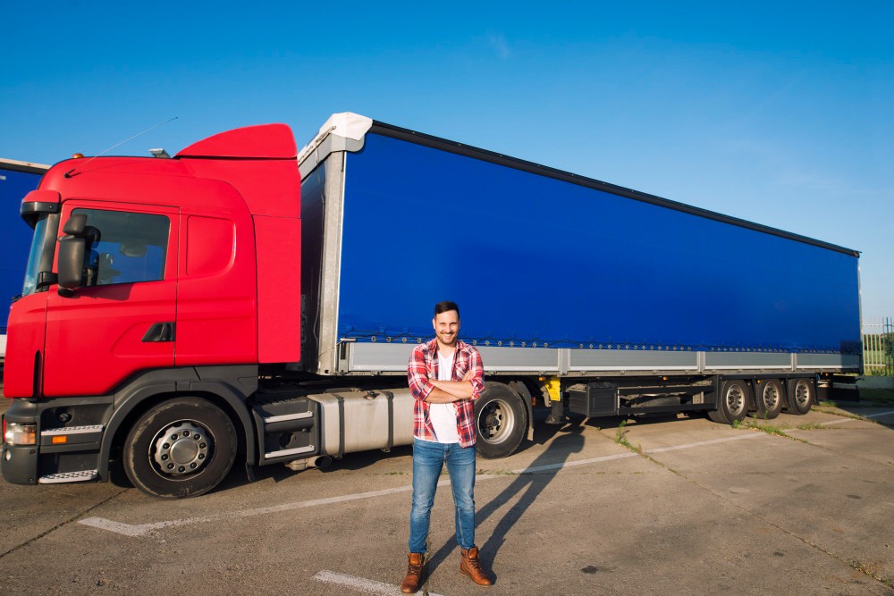 portrait-professional-american-truck-driver-casual-clothing-boots-standing-front-truck-vehicle-with-long-trailer